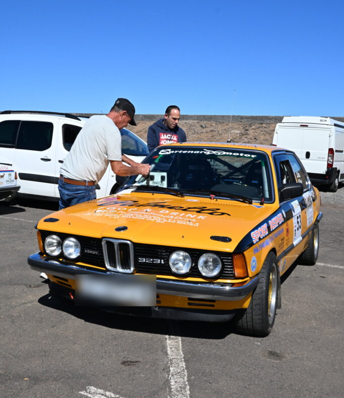 Oranger BMW-Rallyewagen mit Teammitglied in Puerto de la Cruz